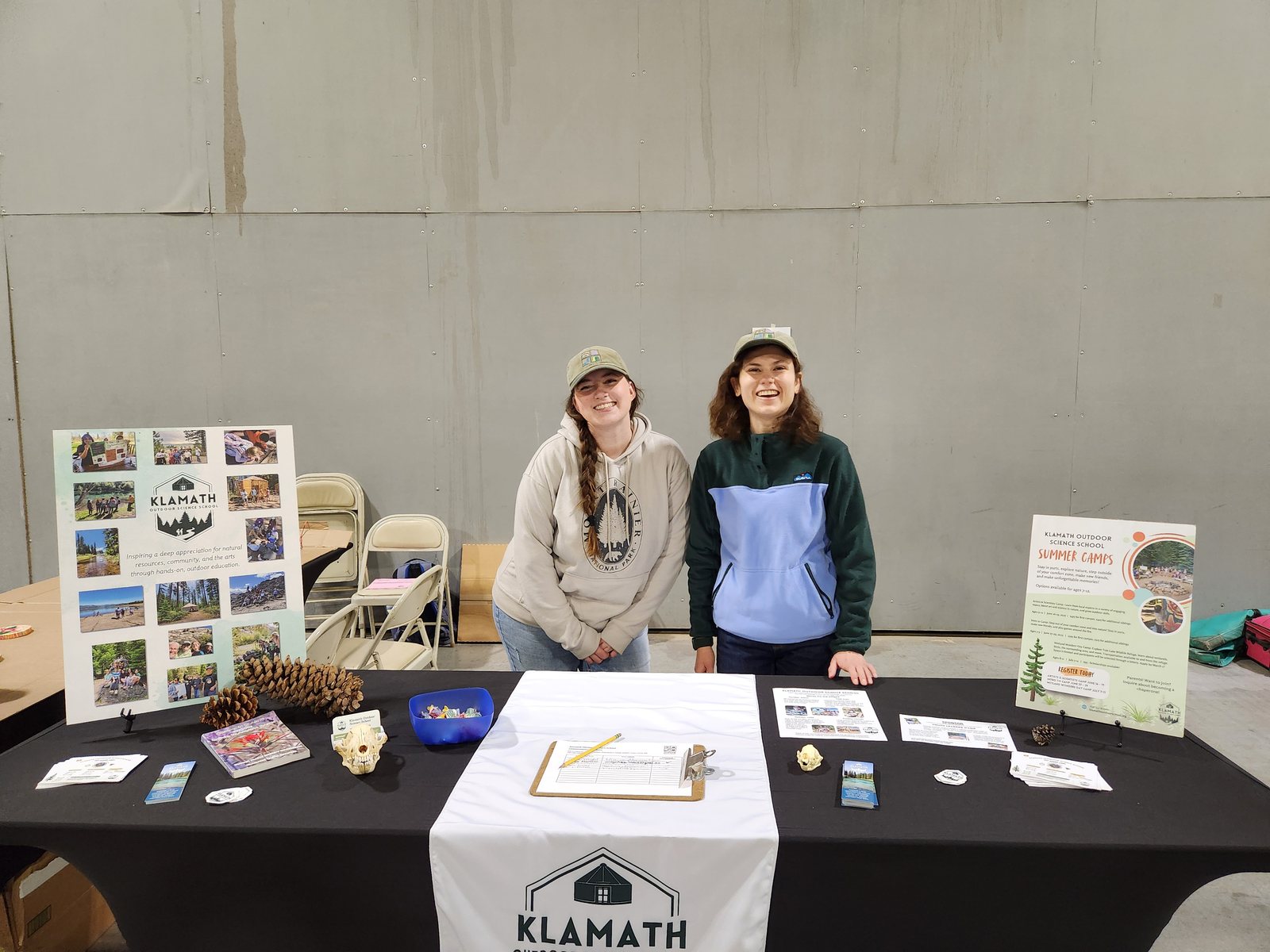 Program Coordinator Mikaela Lea (left) and Executive Director Natalie DiNenno (right) pose with the KOSS table, which included new summer camp flyers, stickers, and bookmarks.