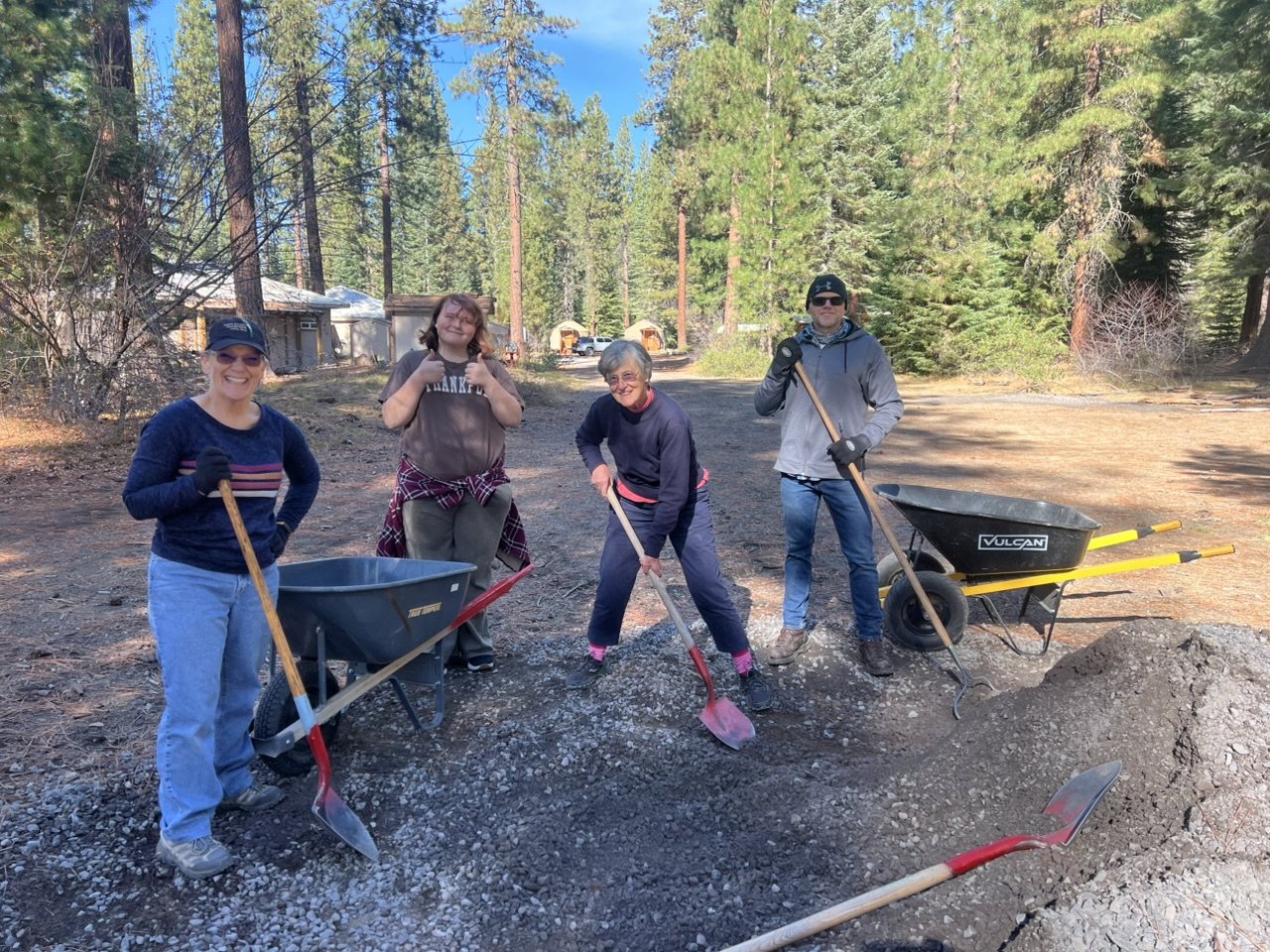 Lots of volunteers smiling while using shovels and rakes