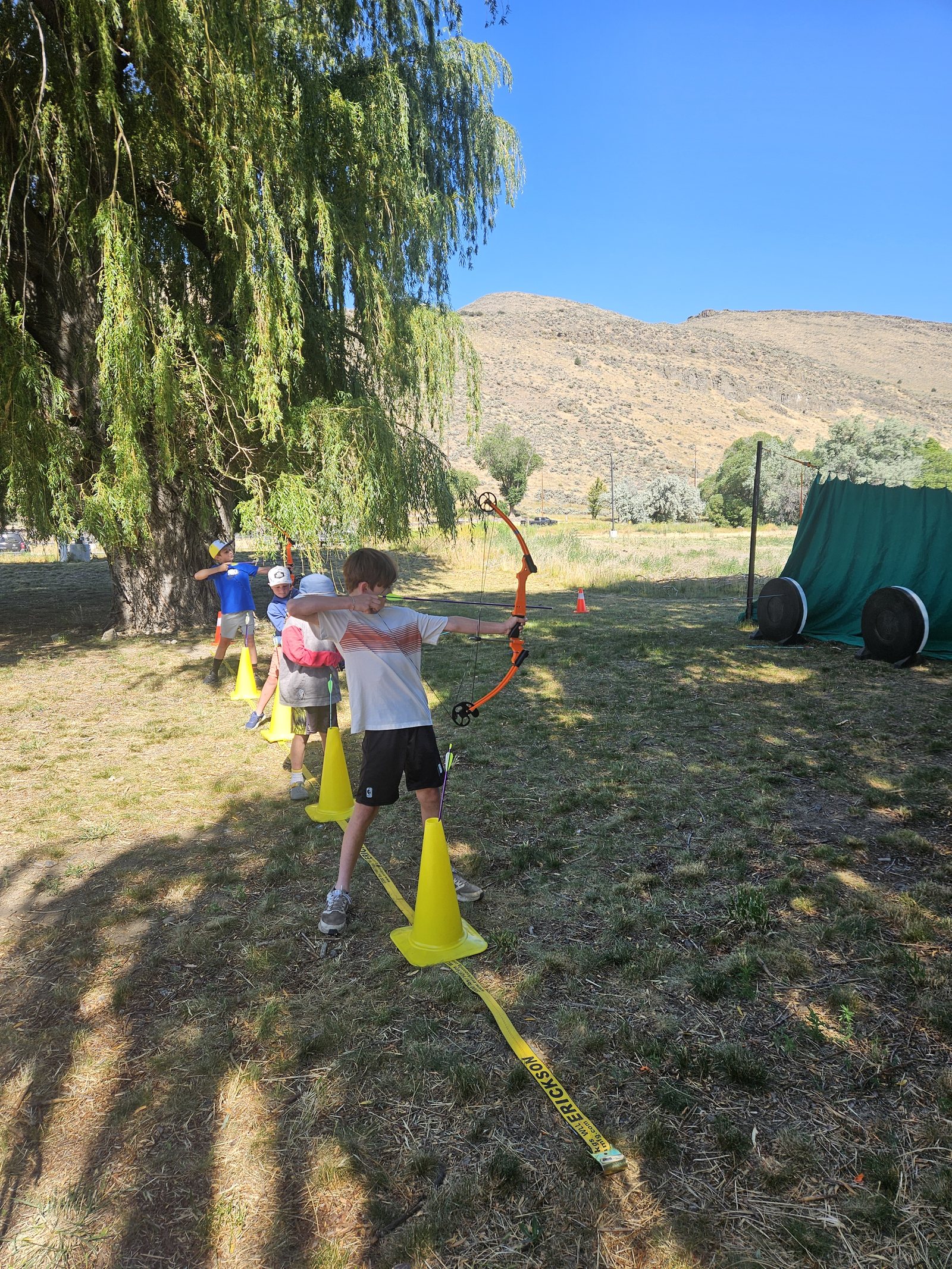 Campers learning proper techniques for archery while aiming at targets