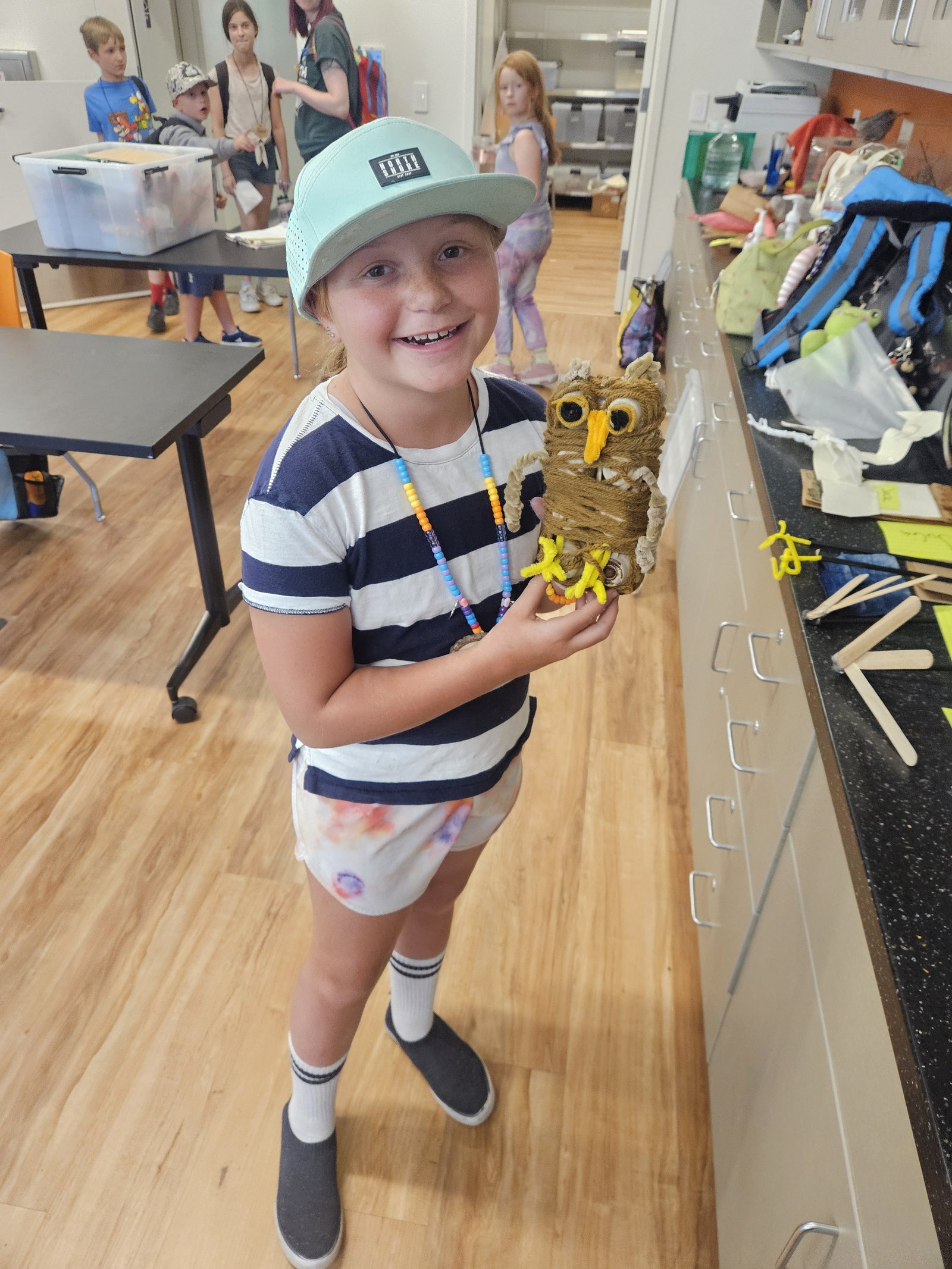 A camper showing off her model of a Great horned owl