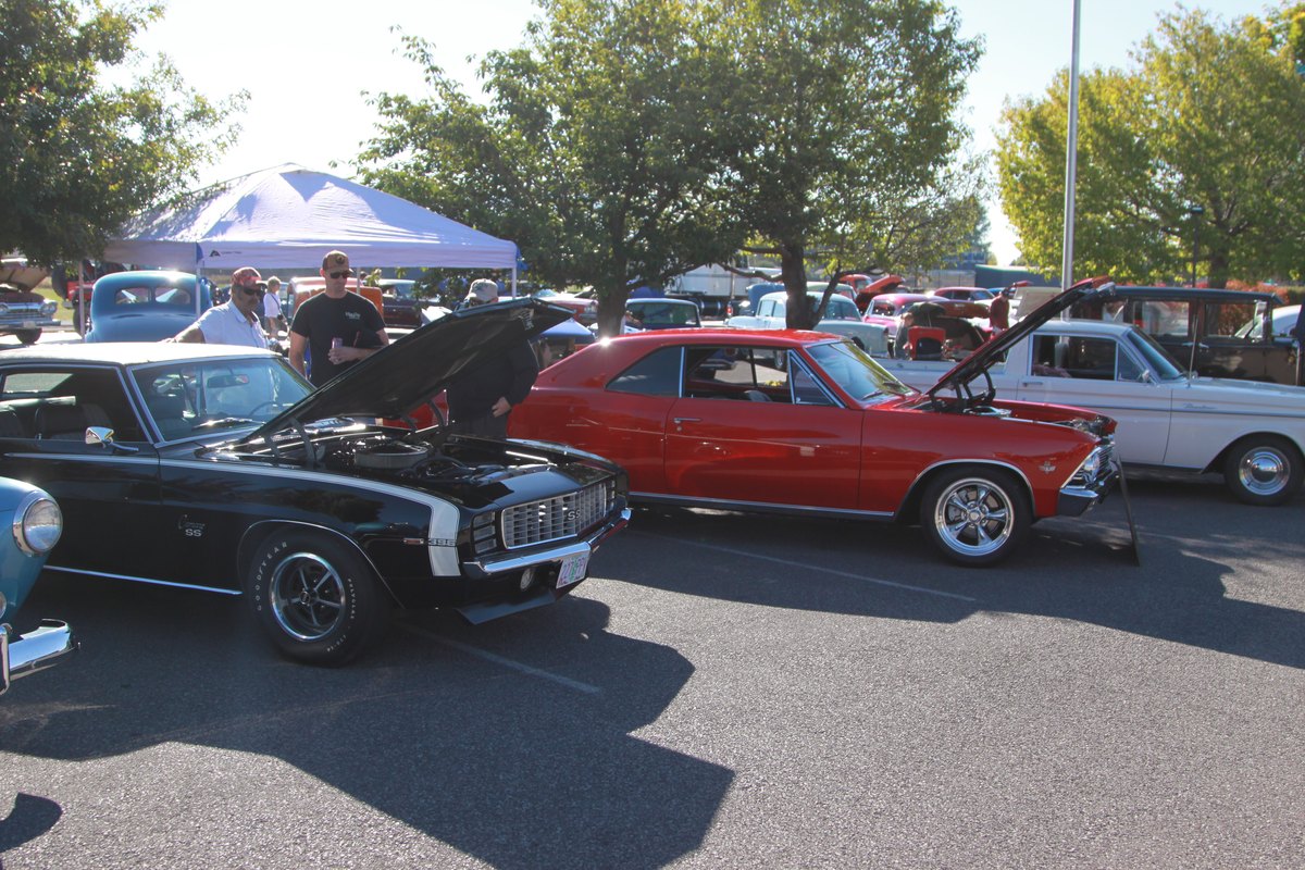 Classic cars lined up under pop-up tents at a Crosspoint Christian School car show