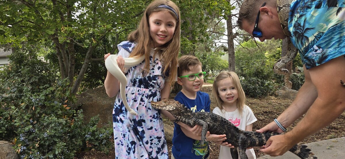 All three kids holding El Chompo the dwarf caiman together