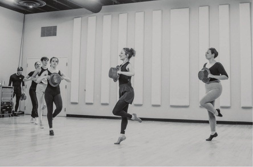 Black-and-white photo of dancers rehearsing choreography in a studio
