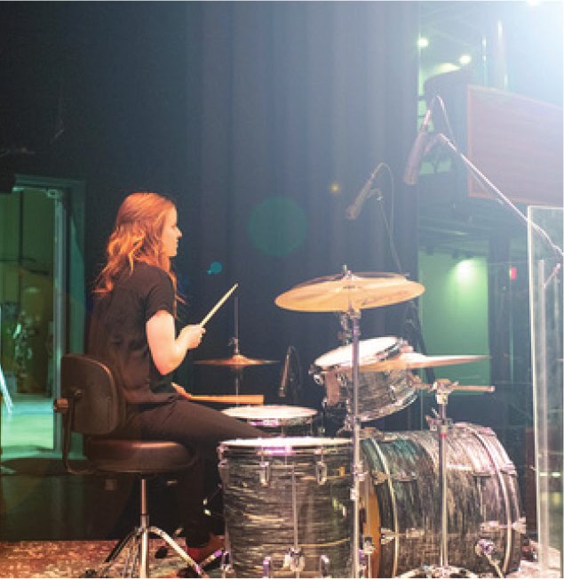 A drummer plays a kit at the side of the Ross Ragland Theater stage