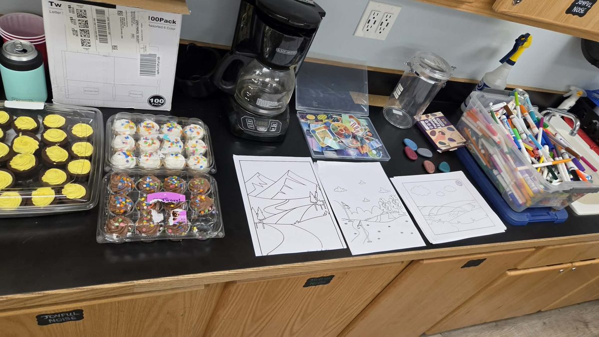 A table of markers, coloring pages and cupcakes set out for a Feelings Forecast workshop