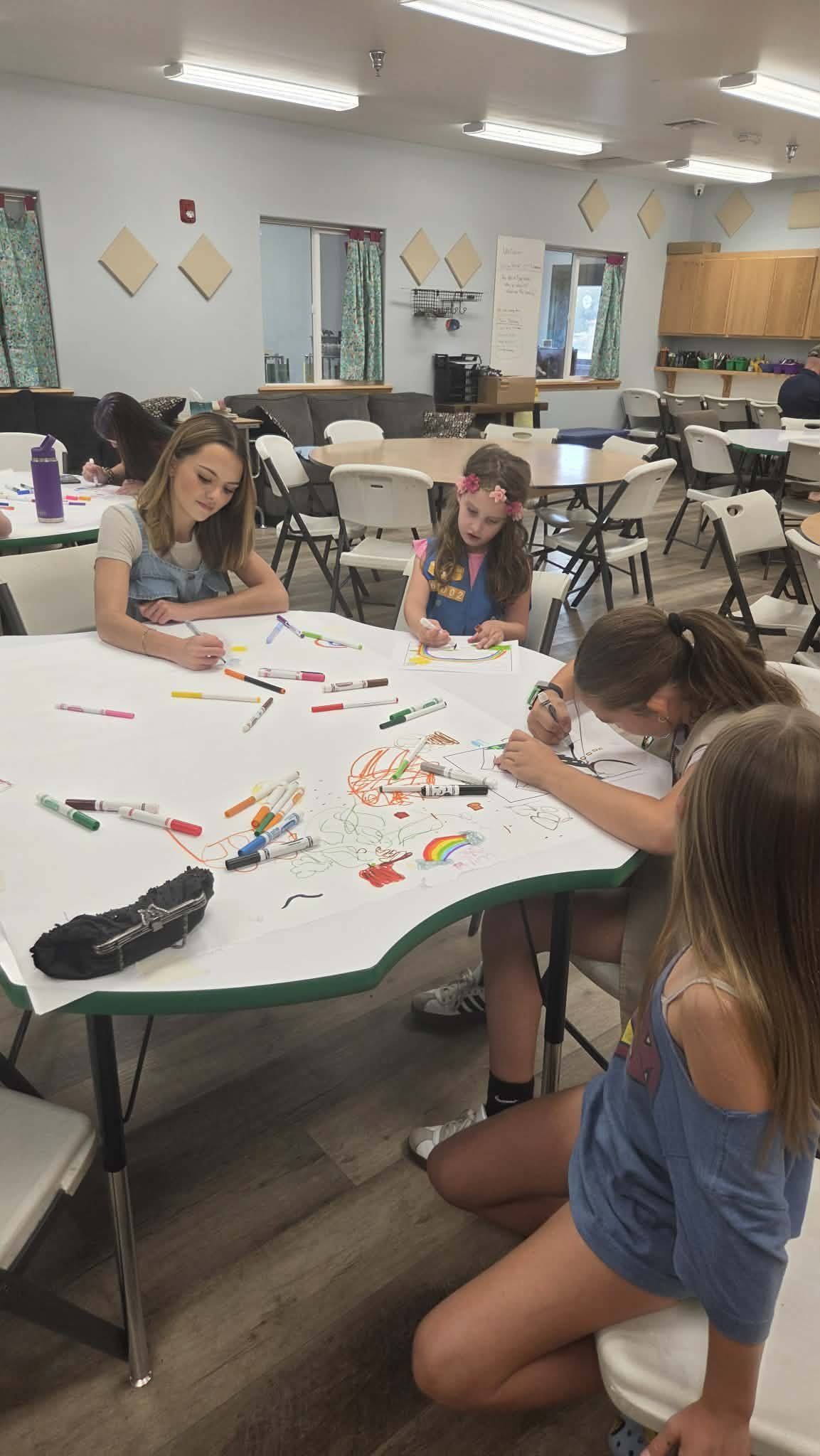 Tenaya Cherrick coloring at a table with three younger Girl Scouts during a workshop