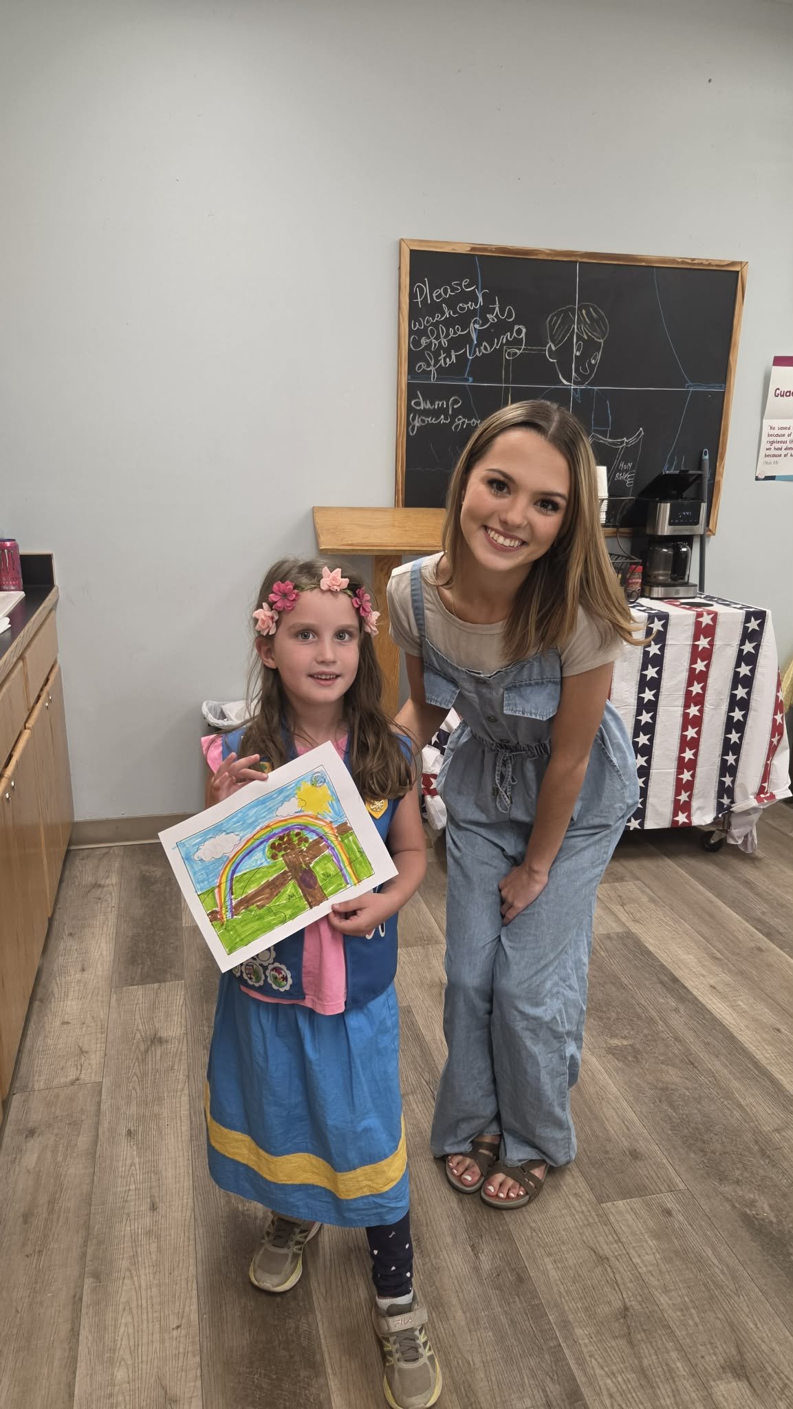 Tenaya Cherrick beside a young Girl Scout holding up her rainbow drawing from the workshop