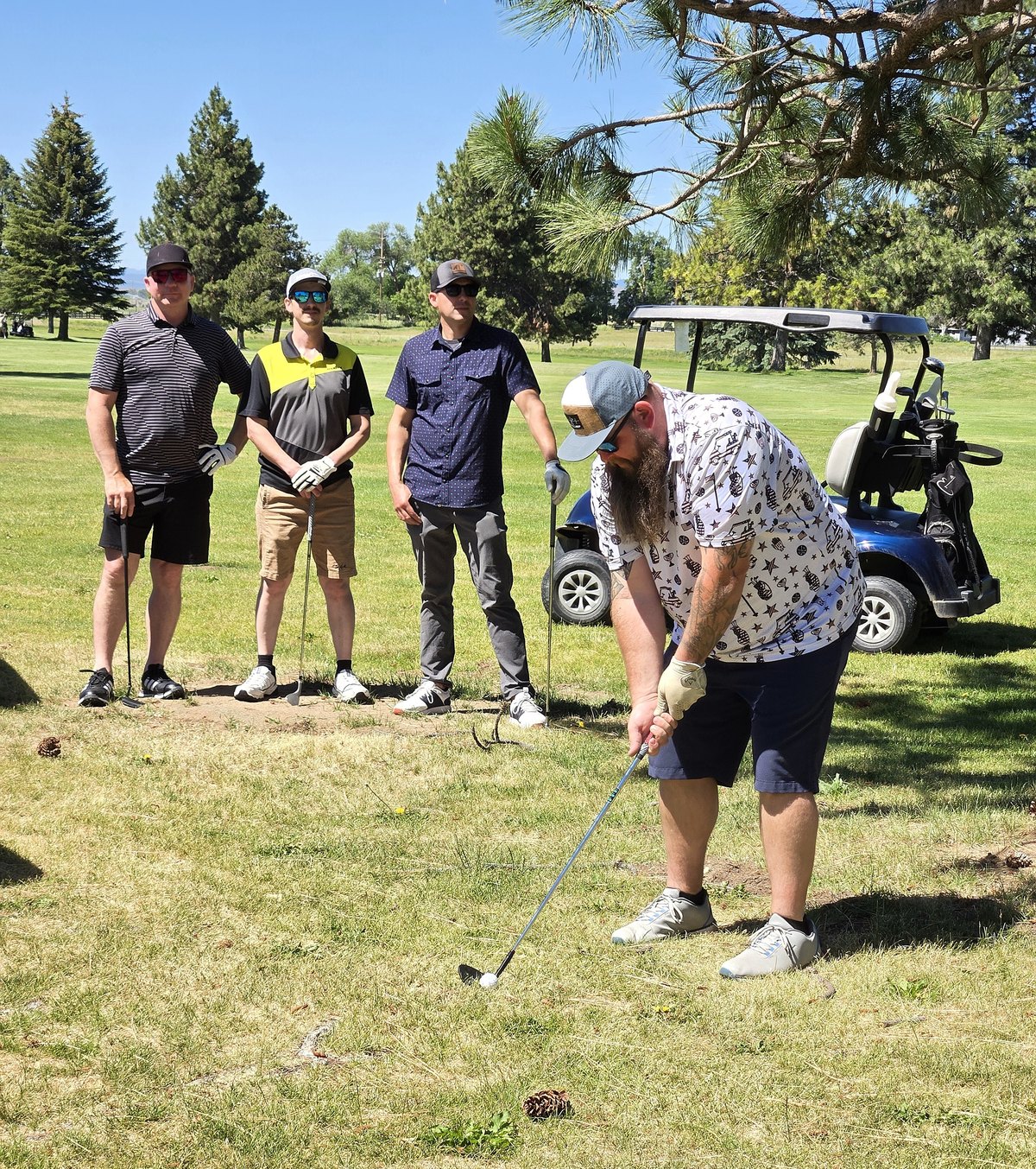 A golfer chips onto the fairway while his teammates watch at the YMCA of Klamath Falls golf tournament