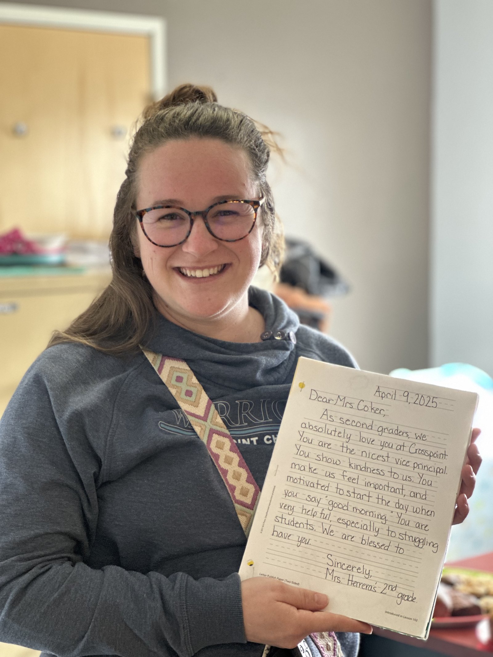 A Crosspoint Christian School teacher holding a handwritten thank-you note from a student